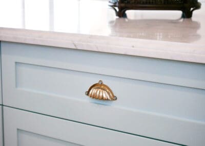 Blue hand-painted kitchen island with chrome handles and marble top featuring lamb’s tongue edging.
