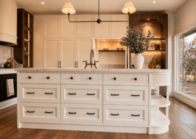 Cream kitchen with hidden appliance garage, fluted island cabinetry, bronze tapware and custom built-in storage.
