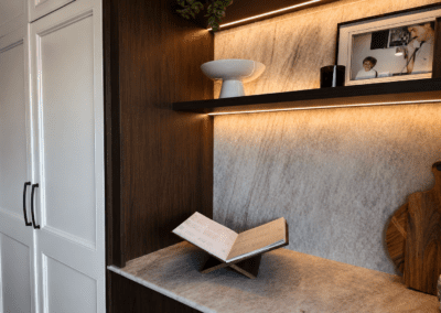 Custom timber display cabinet with illuminated shelves, stone backing and decorative styling.