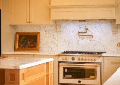 Luxury heritage kitchen cooking zone with marble splashback, Colorado-style custom mantle, gold pot filler tap and cream and gold freestanding range oven