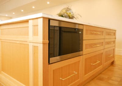 Handcrafted timber kitchen island with decorative panel detailing, integrated microwave drawer and brass bar handles in heritage Croydon Park kitchen