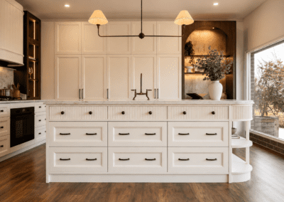 Front view of a fluted kitchen island with stone benchtop, provincial drawers and floor-to-ceiling cabinetry in the background.