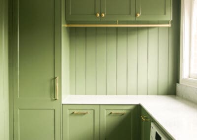green laundry cabinetry wall featuring full-height custom joinery, gold hanging rail, vertical beadboard panelling and marble benchtop in Croydon Park heritage home