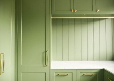Close up of sage green Waratah-profile laundry cabinetry with polished gold pull handle and marble benchtop edge in heritage Sydney laundry renovation