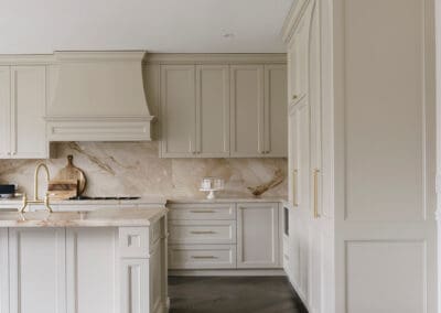Traditional custom kitchen featuring floor-to-ceiling Chiefly cabinetry, a stone island, satin brass hardware and dark herringbone timber flooring.